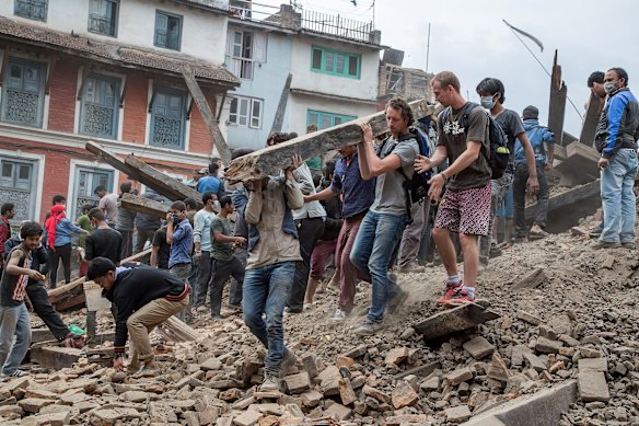 Emergency workers and bystanders clear debris while searching for survivors under a collapsed temple in Basantapur Durbar Square following an earthquake in Kathmandu, Nepal.