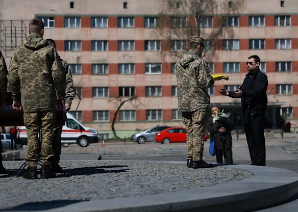 Andriy Dorozhko is presented with the Ukrainian flag during the burial of his father, Ukrainian soldier Victor Dorozhko, in Lviv. Dorozhko was killed fighting against the Russian military near the city of Popasne.