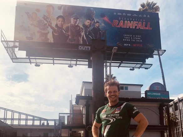 Australian actor Zac Garred in front of a billboard for the film Occupation Rainfall on Sunset Boulevard in Los Angeles. The sci-fi sequel was reportedly a hit on Netflix, yet Garred - who acted in and produced it - has never seen a cent in residuals.
