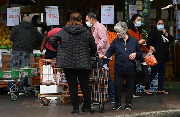 Customers in front of a fresh fruit and vegetable shop in Fairfield. Shops are still shuttered and residents are largely confined to their houses or apartments in the local government area of Fairfield, which has been subject to the harshest restrictions in NSW since surveillance testing for workers was first introduced in July.