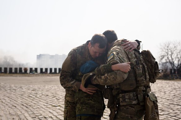 Ukrainian servicemen comfort Daniil, 12, after his father's burial. 