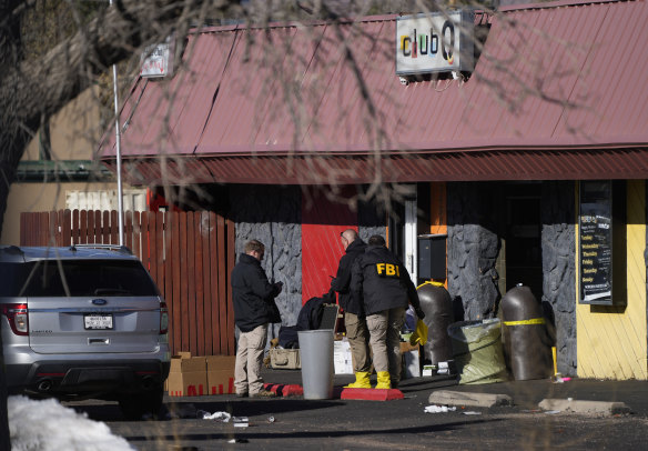 Law enforcement investigators exit Club Q, the site of a weekend mass shooting. “ loading=