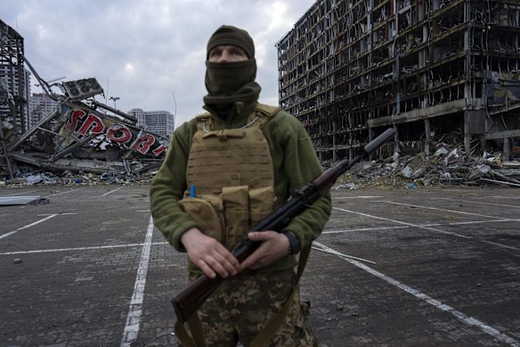 A soldier poses for a picture in Kyiv while standing guard amid the destruction caused after shelling of a shopping center on March 21st.