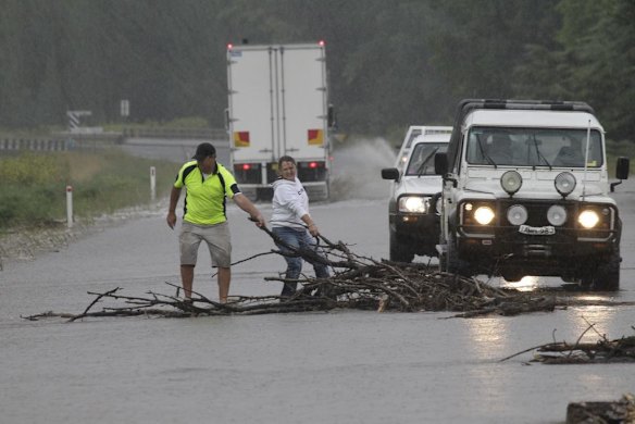 Motorists remove debris from the flooded Monaro Hwy at Bunyan near Cooma in southern NSW.