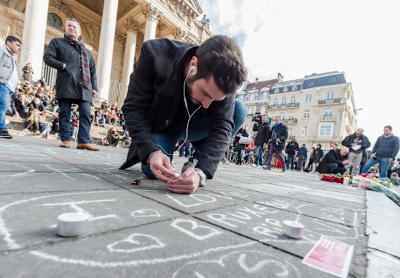 A man lights a candle at a memorial outside the stock exchange in Brussels on Tuesday