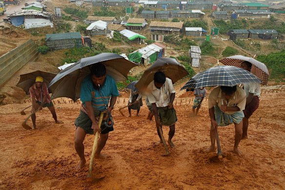 In preparation to battle the monsoon flood waters a group of men work in the rain to create drainage on the side of a cliff in Kutupalong Camp. 
