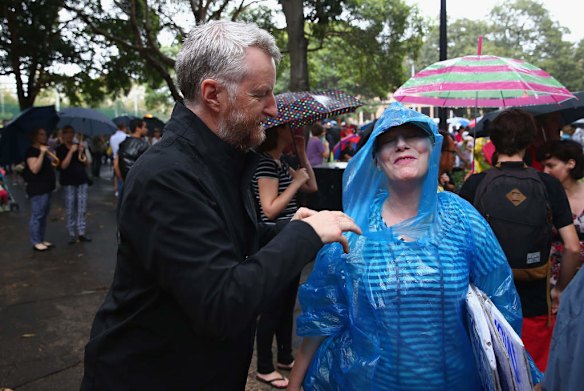 SYDNEY, AUSTRALIA - MARCH 16:  Billy Bragg helps a fellow protester with her poncho during a protest demonstration against the Abbott led Coalition Government on March 16, 2014 in Sydney, Australia. March In March is a nationwide grassroots protest organized to deliver a statement of no confidence in the current Australian Government.  (Photo by Don Arnold/Getty Images)