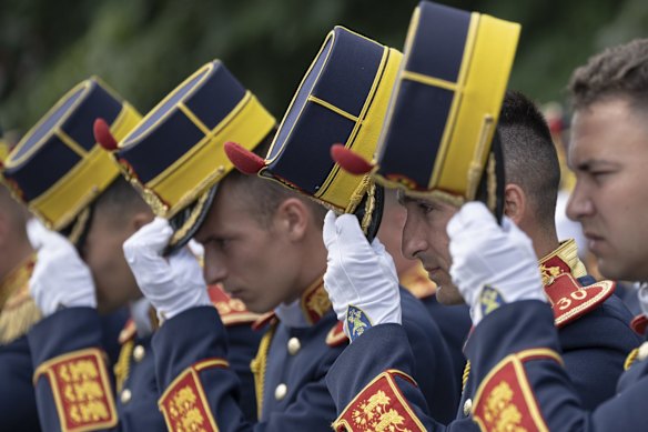 Honor guard soldiers remove their hats during a ceremony for Aviation Day which celebrates aviators, military and civilian, who lost their lives in the line of duty or contributed to the evolution of Romanian aviation. in Bucharest, Romania.