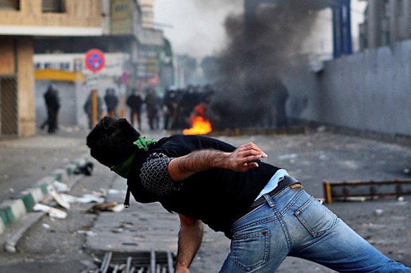 In this photograph posted on the internet, a protester recoils after throwing a projectile at Iranian riot police in Tehran, Iran Saturday June 20. 2009.