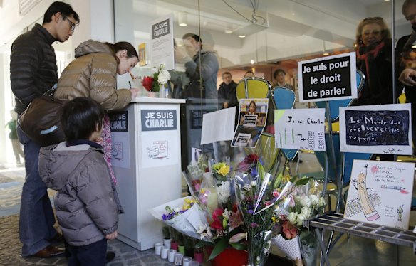 A family signs the "Je suis Charlie, or I am Charlie" condolence book at the French Institute in Tokyo Sunday, Jan. 11, 2015 in support of the victims who were shot by terrorists at the Charlie Hebdo satirical journal in Paris last week. More than 200 French residents, their family and Japanese attended a special memorial gathering at the institute to decry the terrorism in which 17 people and three al-Qaida-inspired gunmen were killed over three days of bloodshed at the offices of the newspaper, a kosher supermarket and other sites around Paris.