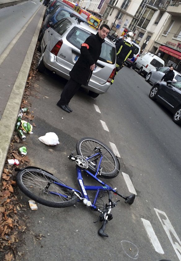 Police guard the bicycle of an officer hit by a car during the shootout. The shell of a bullet is circled, bottom right.