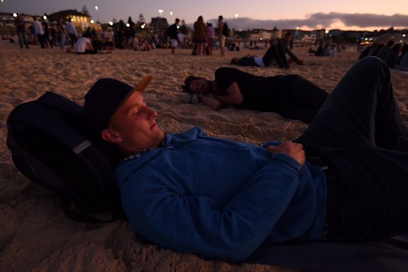 Leon Brach 19 from Germany watches the sun rise over Bondi Beach.
