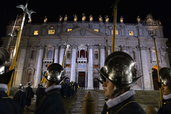 Swiss guards arrive at the balcony where the new pope will appear is seen in the background minutes after white smoke rose.
