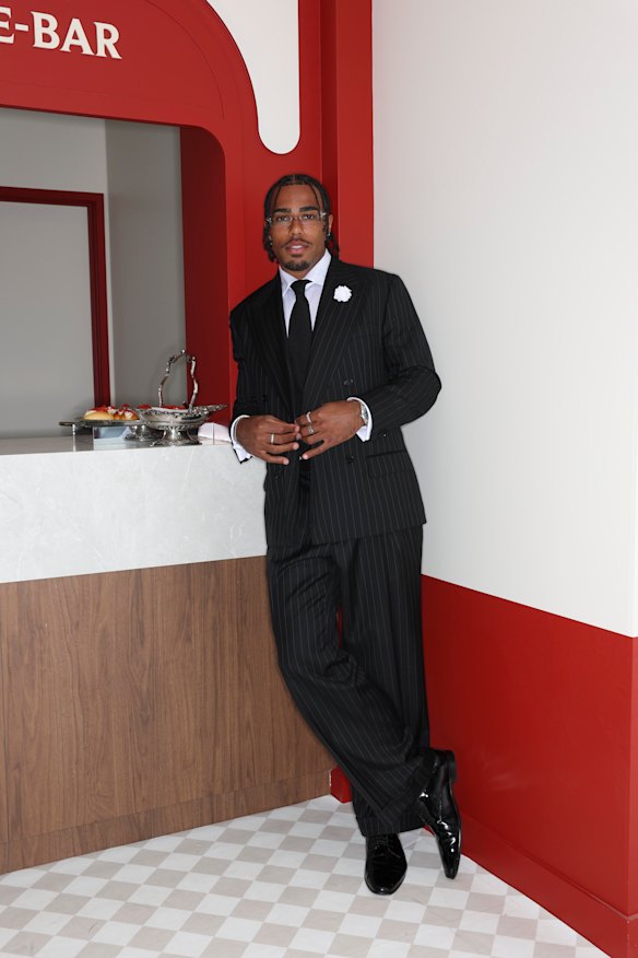 Isaac Quaynor wearing a pinstripe Oscar Hunt suit inside the G.H. Mumm pavilion at Derby Day. 