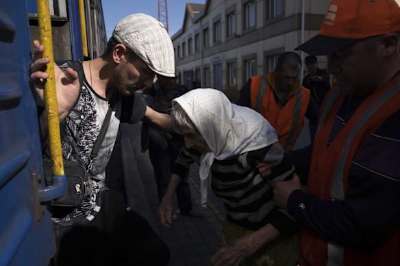 People help a disabled elderly woman onto an evacuation train in Pokrovsk.