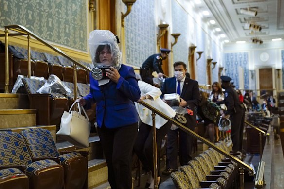 People wearing gas masks shelter in the House gallery as protesters try to break into the House.