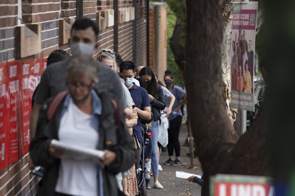 People wait to vote outside Erskineville Primary School on council election day. 