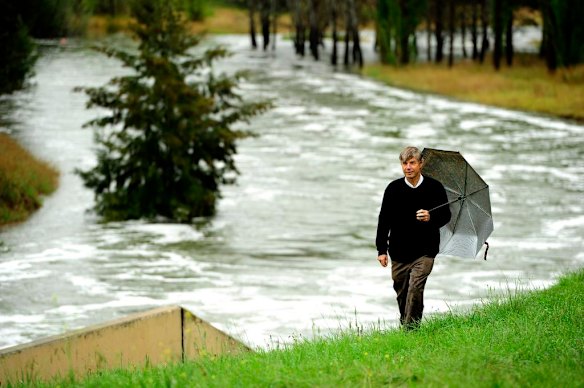 John Connelly watches water flow out of Lake Ginninderra in to Ginninderra Creek.