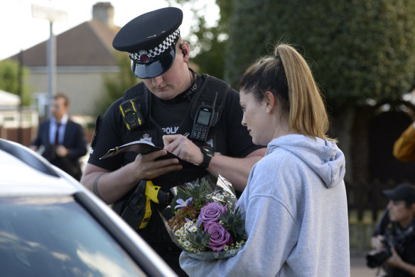 A woman speaks to police before laying flowers at the scene of the attack. 