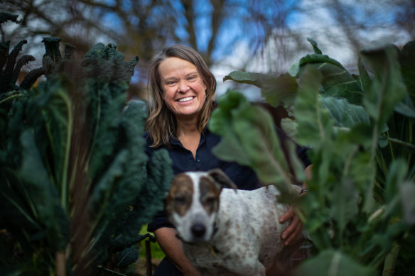 Gardening Australia host Millie Ross and her dog, Squid, in the midst of some leafy greens in her garden. 
