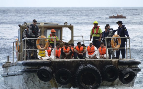 Australian Customs officials and navy personnel escort asylum seekers to Christmas Island in 2013. 