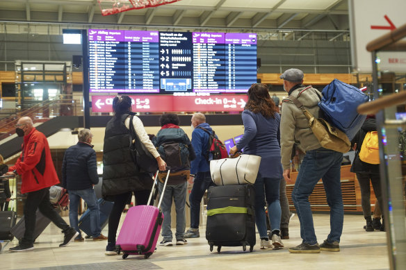 Travellers stand in front of an information board at BER Airport in Berlin, Germany, on Saturday.