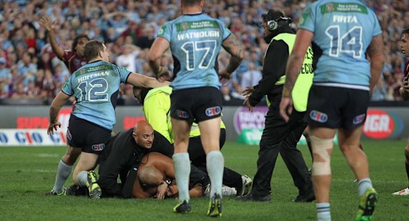 Security guards tackle a streaker towards the end of the first half.