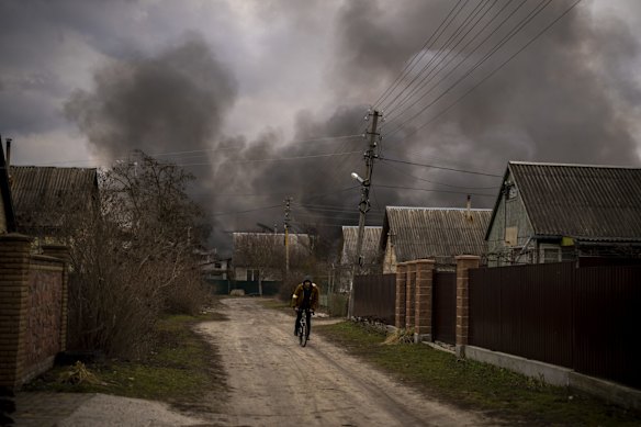 A Ukrainian man rides his bike near through a heavily bombarded Irpin.