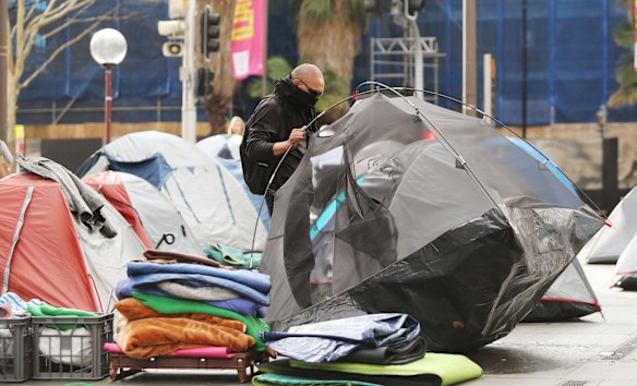 A man removes a tent from Tent City.
