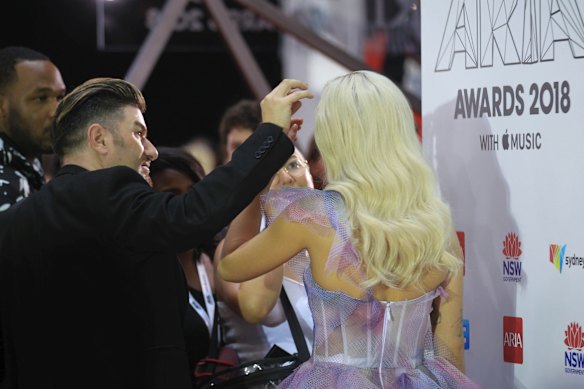 Girl's got to look good: Rita Ora having her hair and makeup touched up before posing on the media wall.