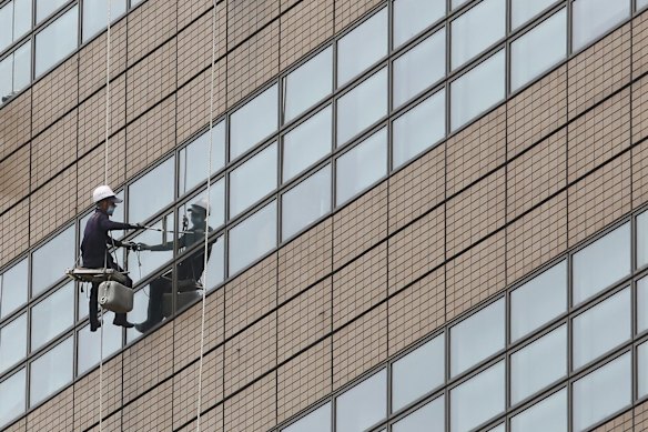 A worker wearing a face mask to help protect against the spread of the new coronavirus hangs on a rope to clean the windows of an office building in Seoul, South Korea, Saturday, June 6, 2020.
