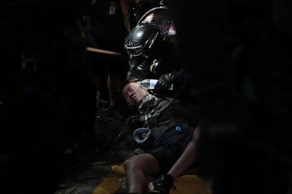 A policeman pours water on the face of a detained protester.