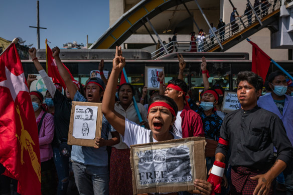 Protesters hold placards and shout slogans. 