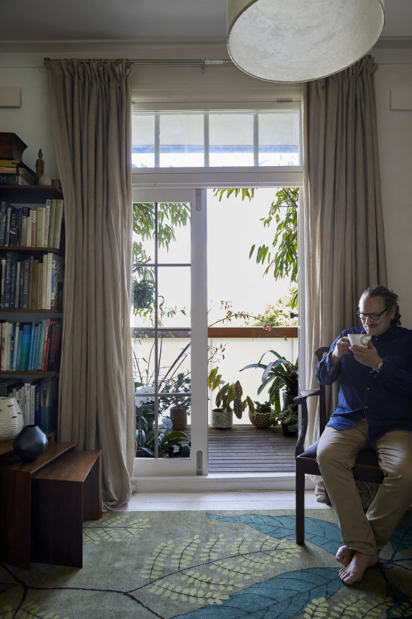 Longmuir sits on an 18th century mahogany chair next to French doors opening to his balcony. “I love the high ceilings and district views over Paddington.”