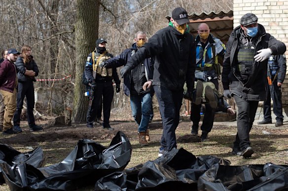 Volunteers carry dead bodies from a basement to a morgue in Bucha.