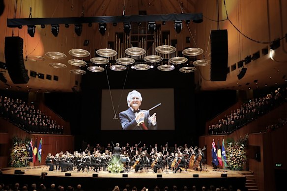 The Sydney Symphony Orchestra performs at the state memorial service for Bob Hawke, who is shown conducting Handel's Messiah in the Concert Hall a decade ago.