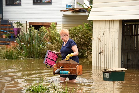 A resident carries out water logged items from her house on a flooded Bright street in Lismore. 