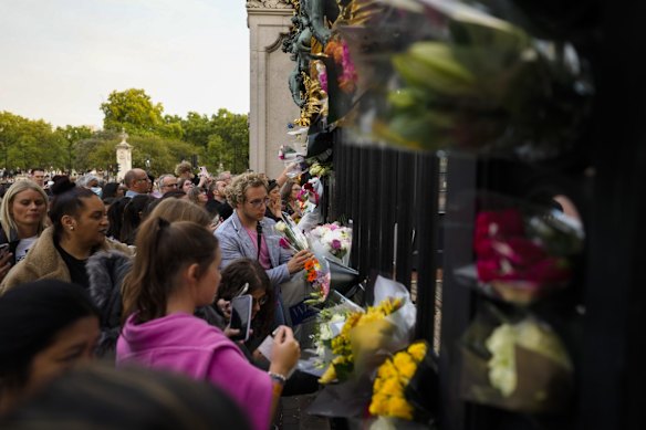 People lay flowers outside the gate of Buckingham Palace in London, United Kingdom.   