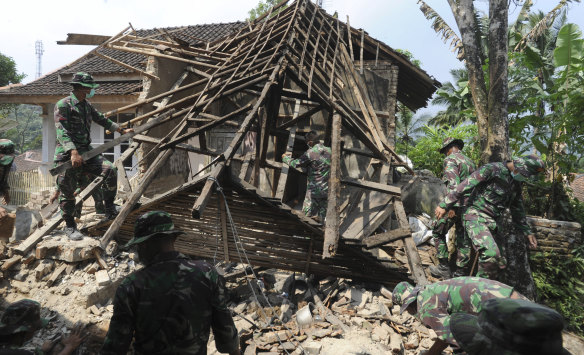 Indonesian soldiers remove debris from a house damaged by a strong earthquake.