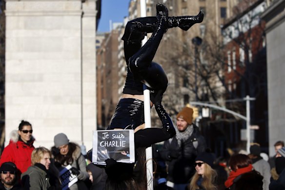 Street performer Carolyn Chiu holds a "Je Suis Charlie" (I am Charlie) sign during her act as several hundred people gather in solidarity with victims of two terrorist attacks in Paris, one at the office of weekly newspaper Charlie Hebdo and another at a kosher market, in New York's Washington Square Park, Saturday, Jan. 10, 2015. 