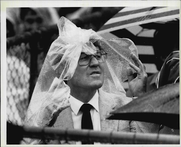 Roy Masters uses a sheet of plastic to shelter from rain in 1985. 
