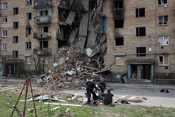 Local residents sit by the makeshift stove in the courtyard of a heavily damaged apartment building  in Horenka, near Kyiv.