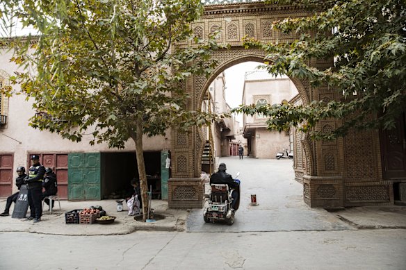 Police officers stand guard on a street as a motorist drives past in Kashgar, Xinjiang autonomous region, China.