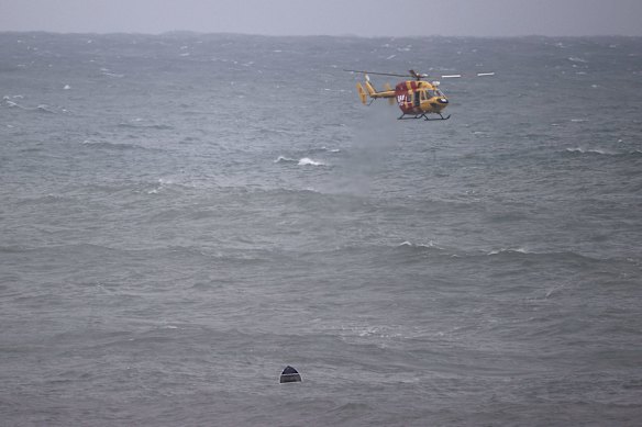 Search crews look for survivors as a small aluminium boat sinks offshore in the big swell at Bondi Beach. Police later confirmed the owner was safe and well, and had last seen his boat moored at Gordons Bay.