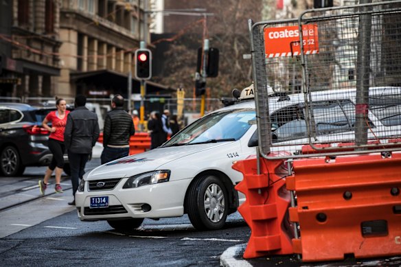Pedestrians and cars navigate the construction of the light rail at the intersection of George Street and Bridge Street,