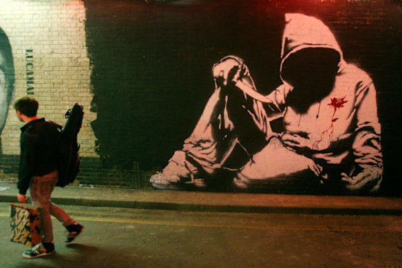 A man walks past a piece of street art by Banksy in London. The work was completed as part of the "Cans" exhibition by graffiti artists.