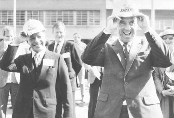 Premier John Cain has trouble finding the correct size for his hard hat after the official opening of Jack Chia's South Yarra Project. 1984