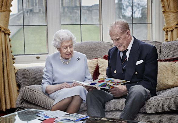 Queen Elizabeth II and Prince Philip, Duke of Edinburgh look at their homemade wedding anniversary card, given to them by their great grandchildren Prince George, Princess Charlotte and Prince Louis, in the Oak Room at Windsor Castle ahead of their 73rd wedding anniversary, on November 17, 2020 in Windsor, England. 