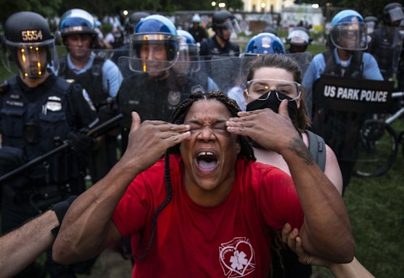 A woman reacts to being hit with pepper spray as protesters clash with US Park Police after they attempted to pull down the statue of Andrew Jackson in Lafayette Square, Washington DC on June 22, 2020. Protests continued around the country after the deaths of African Americans while in police custody.