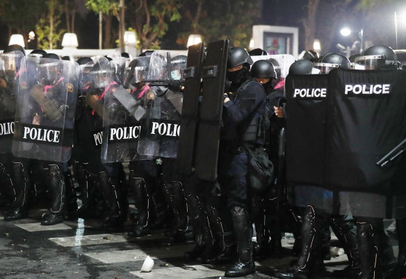 Riot police stand in formation preparing to disperse protesters.